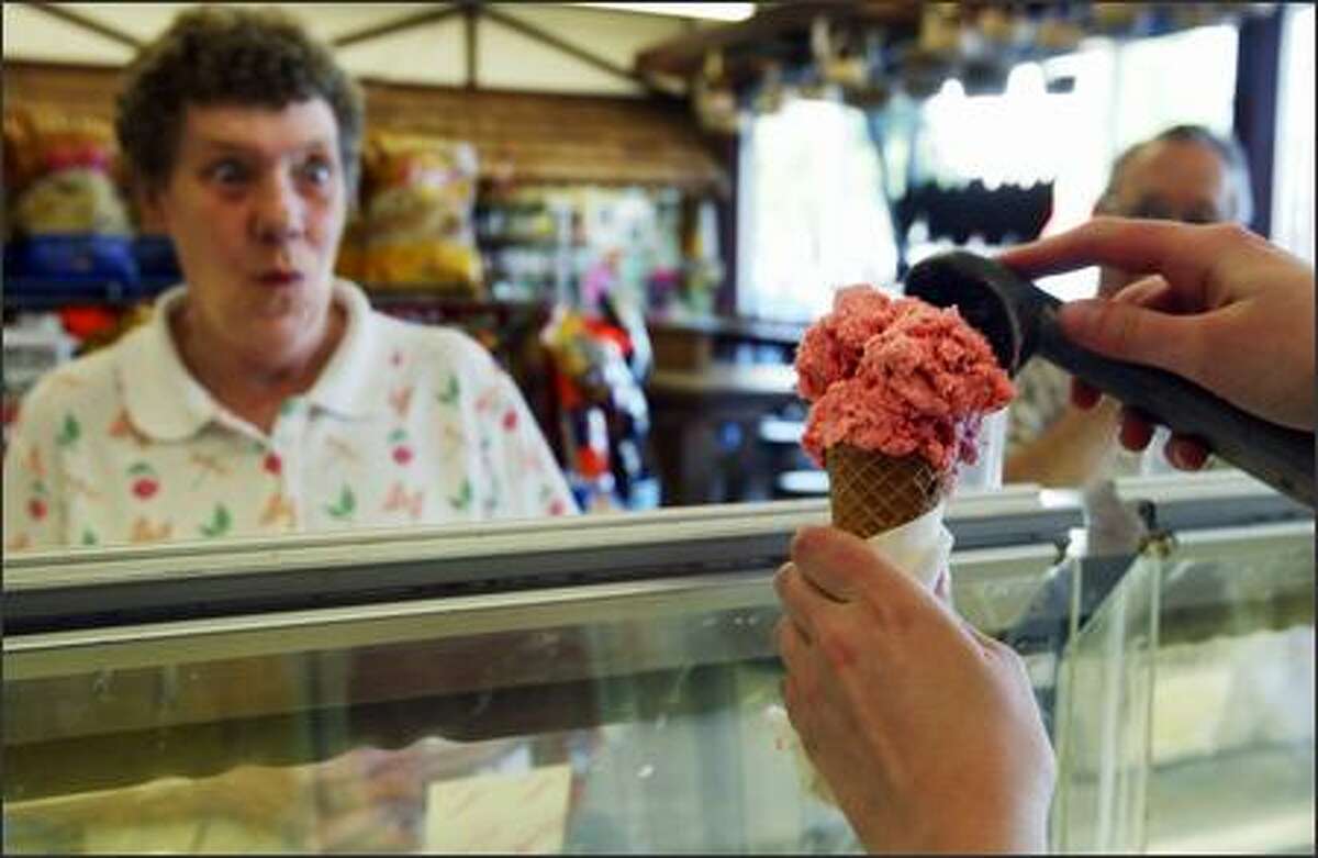 Patty Kottas, left, watches as Devin Dattan scoops out some house-made strawberry ice cream at the Husky Deli. Kottas has been coming to the store since 1960.