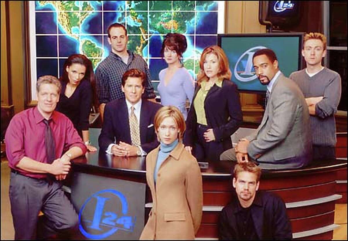 The cast of "Breaking News": Clancy Brown, Rowena King, Paul Adelstein, Tim Matheson, Mindy Crist (standing front), Gabrielle Miller (standing back center), Lisa Ann Walter, Scott Bairstow (seated front), Jeffrey D. Sams, Vincent Gale (New Line Television/Christain Landry).