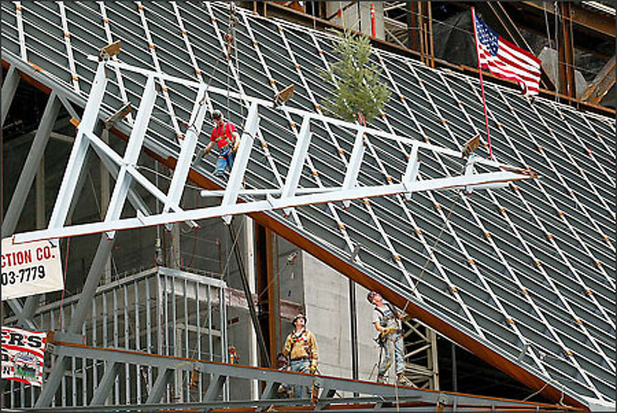 Ironworkers position the last piece of structural steel in the new downtown Seattle Central Library.  The spectacular library was completed on the eve of the Great Recession, which has imposed five consecutive years of cuts to library services.