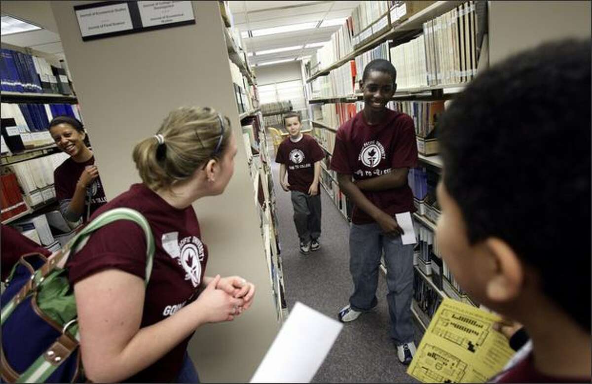 Zion Preparatory Academy fifth-graders Anthony Childs, center; Ethan Rhone, second right; and Giaunie Hendrix, right, walk through the stacks as Seattle Pacific University chaperones Teylar Greer, left, and Whitney Bigger watch Wednesday during a "Library Hunt" at the university.