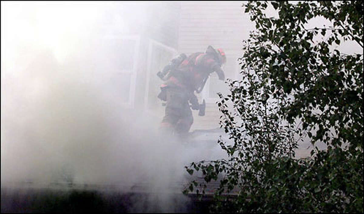 A Seattle firefighter works on a blaze at a two-story house on West Lee Street in Lower Queen Anne. Firefighters were called about 7:15 p.m. yesterday to battle the fire, which destroyed part of the house and filled the neighborhood with acrid smoke. The cause was not known nor was a damage estimate available. There were reports of two injuries -a woman inside the house suffered burns, and a firefighter experienced heat exhaustion.