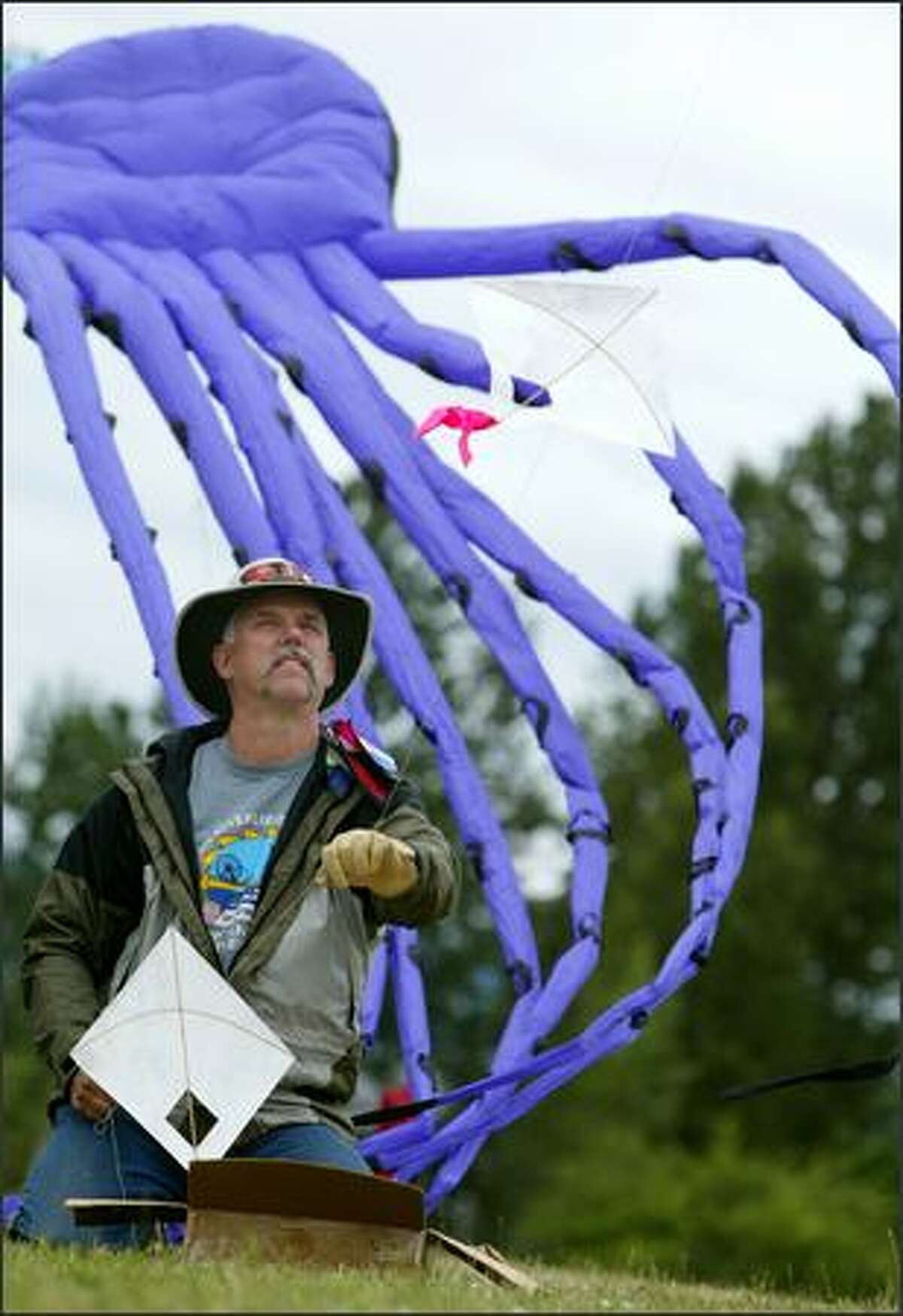Rick White launches a handmade train of 50 kites at Kite Hill at Sand Point Magnuson Park as a giant purple octopus kite launches behind him. Sunday was the Washington Kitefliers Association's annual Father's Day Kite Fly. The event drew a mix of beginning and expert kite fliers.