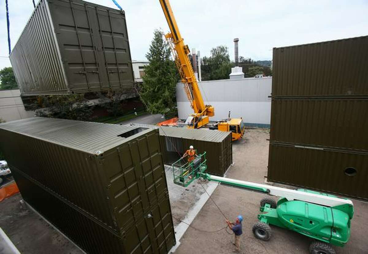 Workers from Fogarty Construction stack shipping containers as they construct a building out of the containers on Thursday in Seattle's Georgetown neighborhood.