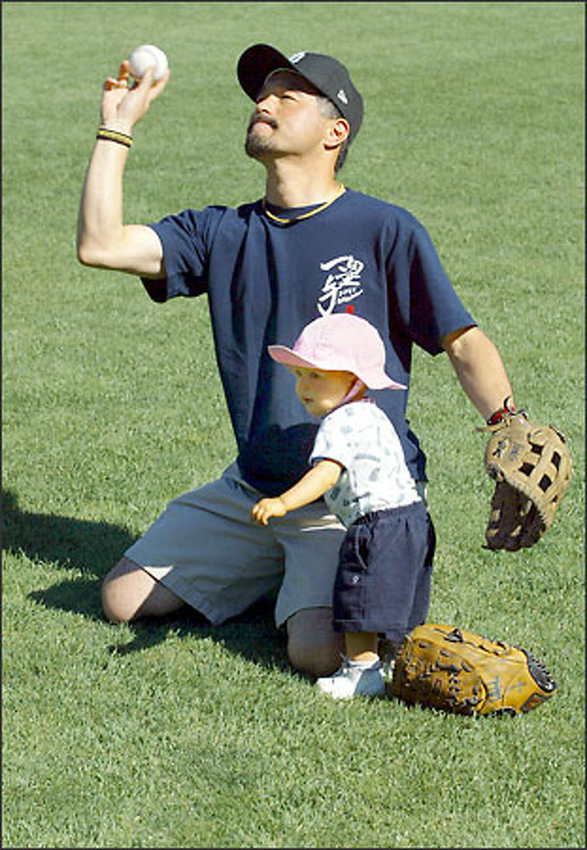 Yoshitaka Inoue tosses a ball to his son yesterday at Safeco Field, while daughter Erina prefers to stay close.