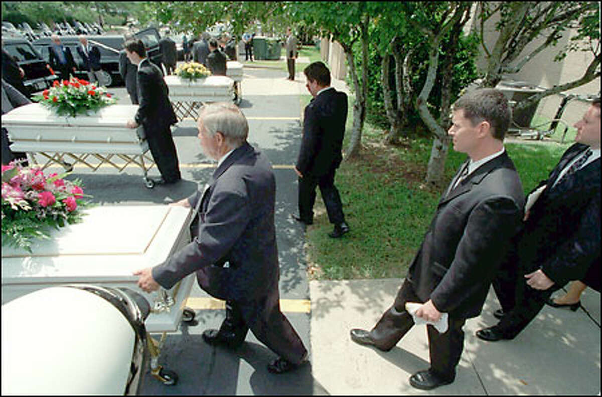Russell Yates, center right, follows behind the casket of his oldest child, Noah, as the caskets of the other four children wait to be loaded into hearses after a funeral service yesterday in Clear Lake, a suburb of Houston.