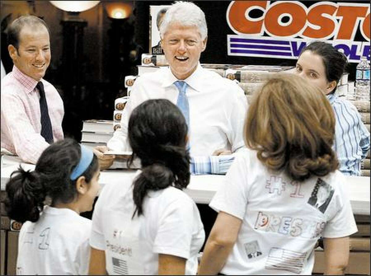 Former President Clinton laughs as fans, left to right, Ava Aminpour, 10, of Bellevue, Shiva Zandi, 14, of San Francisco and Zohreh Zandi of Bellevue show him their homemade "I love the president" T-shirts. Clinton appeared at the Issaquah Costco to sign copies of his autobiography, "My Life."