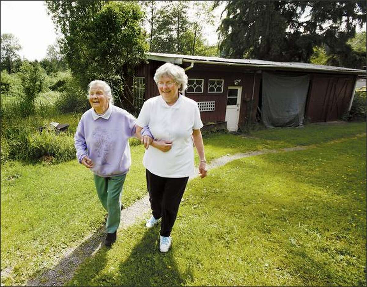Sylvia Vail, Genevieve Tuck's oldest child, helps her mother walk from her painting studio. Tuck lives in the home she and her husband, Lamoine, built in 1955 on acreage near Monroe. Four of Tuck's five children have moved back to the farm.