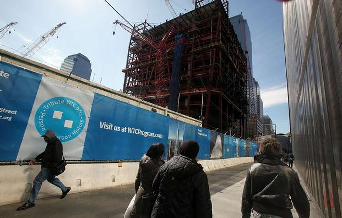 People walk by as work continues on the Freedom Tower at the World Trade Center site in New York in March. A new development agreement announced March 25 will have four office towers eventually constructed after a 16-month stalemate over building at the site.