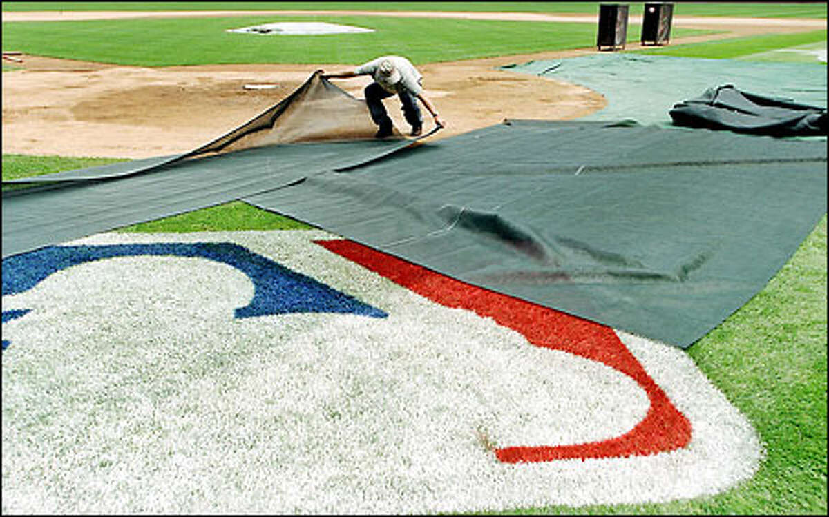 A groundskeeper at Safeco Field measures a mesh tarp for the media to stand on Tuesday during the opening ceremonies for the All-Star Game.