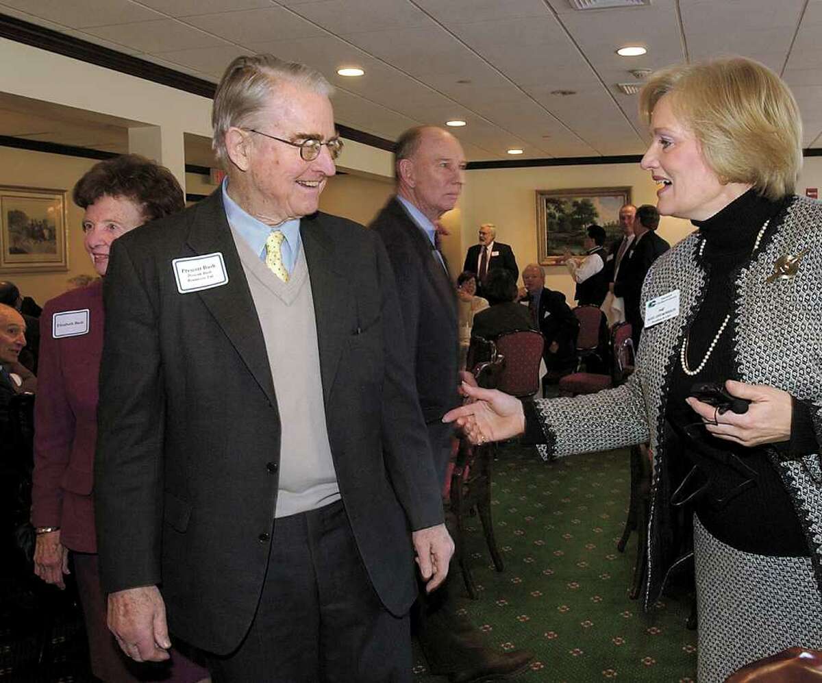In this January 2003 file photo, Prescott Bush Jr., center, and his wife, Elizabeth Bush, left, are greeted by Mary Ann Morrison, of the Greenwich Chamber of Commerce, during the chamber's meeting at the Milbrook Club, Greenwich.