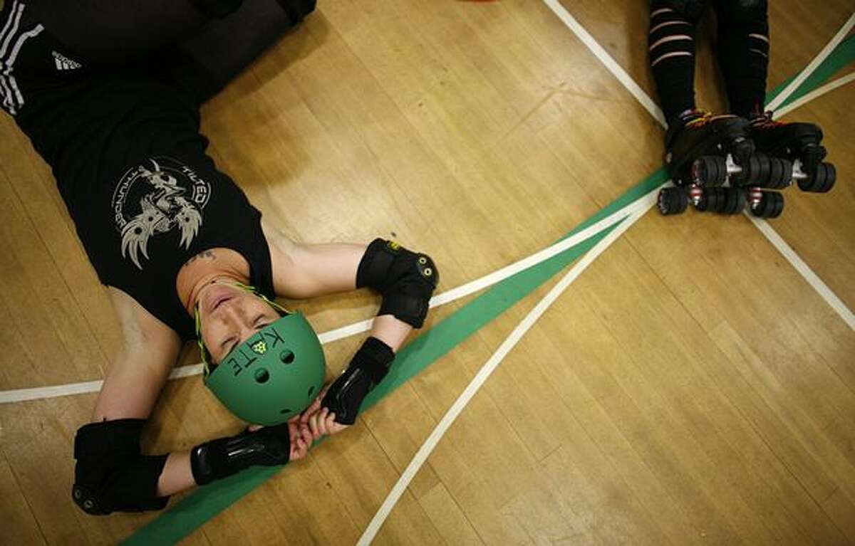 Kate Cioffi of the Tilted Thunder Rail Birds stretches after practice at the Bitter Lake Community Center. The team plans to build a new banked roller derby track.