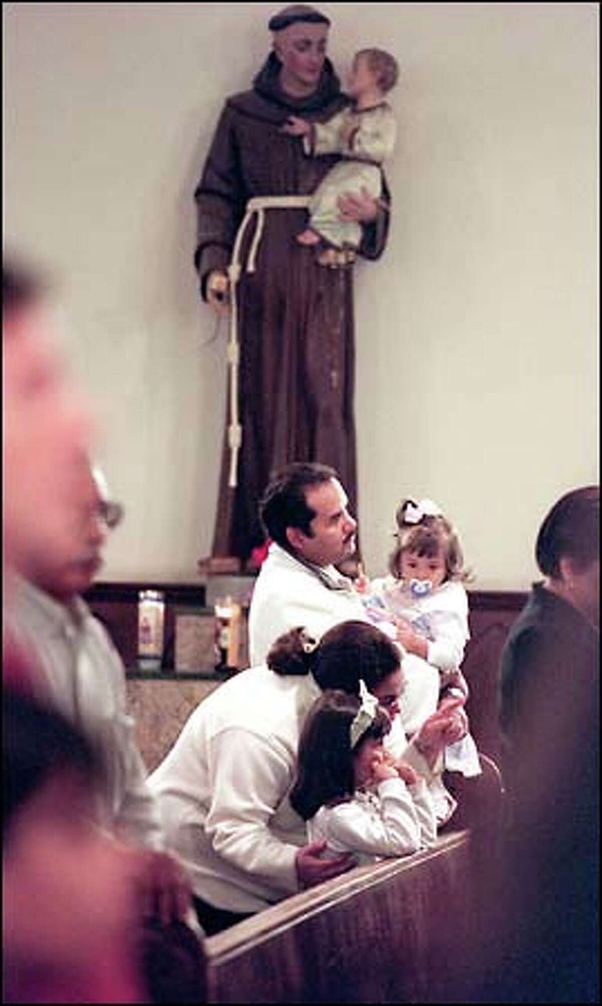 Jose Luis and Marlene Castaneda hold their daughters Manoush, 6, and Maximianne, 1, during their first visit to St. Mary's in the Central District. The Castanedas came to St. Mary's because they had heard it was receptive to Hispanic families.