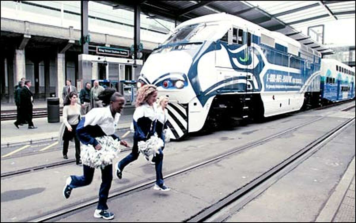 Members of the Seattle SeaGals dash across the train tracks at King Street Station after participating in ceremonies welcoming the "Sounder Seahawk Special" into the city. Sound Transit will offer the service this fall to transport fans to all regular-season Sunday afternoon Seahawks games. A roundtrip ticket from Tacoma, Puyallup or Sumner is $8; $6 if the train is boarded in Auburn, Kent or Tukwila. For more information check out www.soundtransit.org/sounder/timetables/SdrseahksTrain2002.htm.