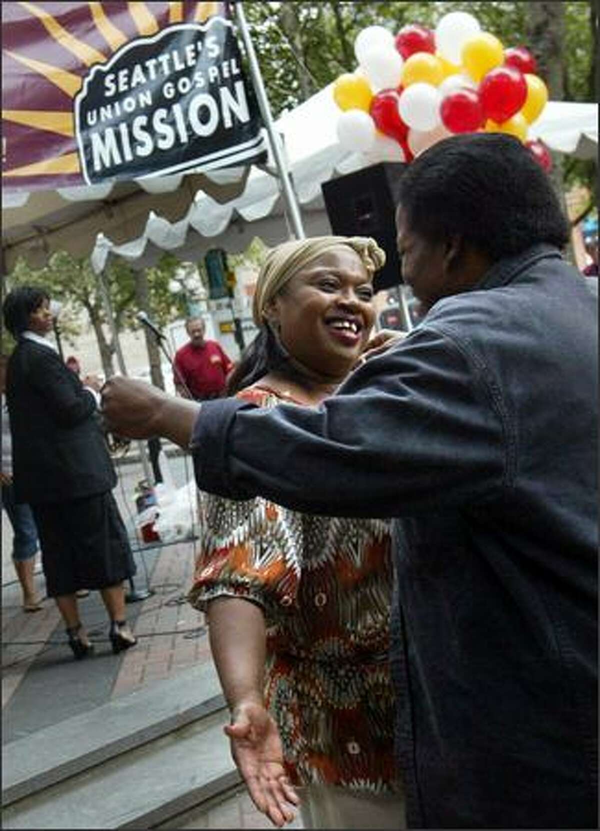Gospel singer Josephine Howell hugs Raama Hunter at the Union Gospel Mission's 75th anniversary celebration Tuesday at Occidental Park. During her performance, Howell spoke about how she lived on the streets with her children for five years until she discovered the Union Gospel Mission.