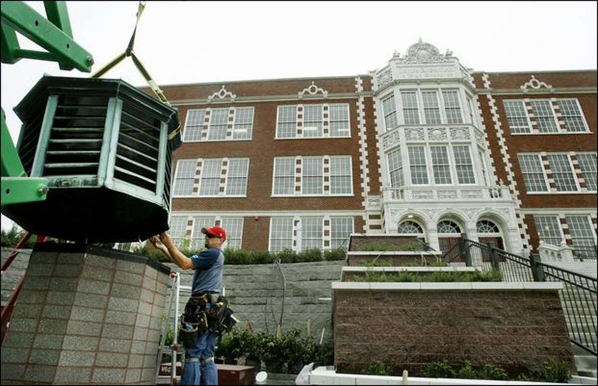 Mike Cowger of Northshore Sheet Metal Inc. of Everett helps position an exhaust vent, moved from the roof of Garfield High School, into position to serve as a lighting fixture outside the newly renovated school. The $107 million renovation is the most expensive attempted by Seattle Public Schools.