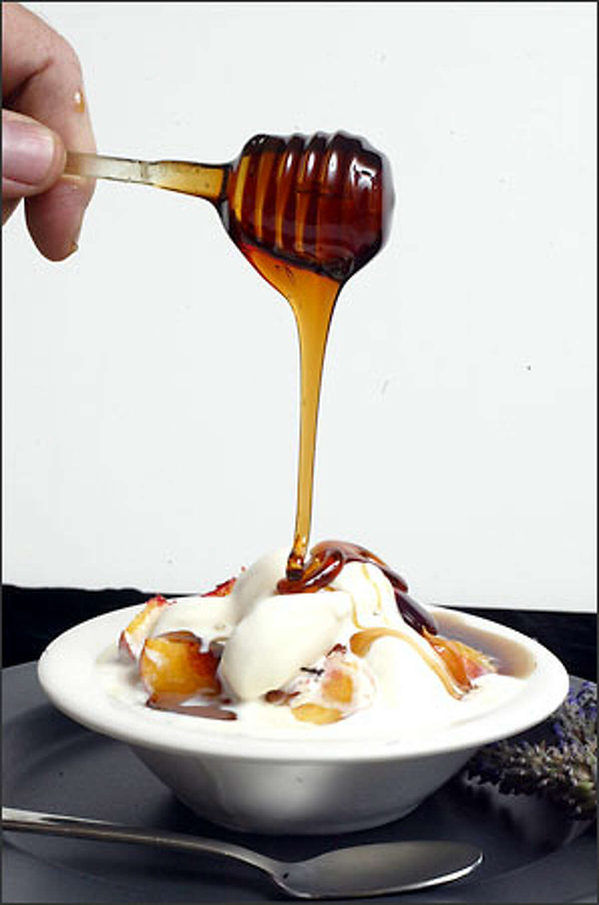 Beekeeper Tim Celeski drips honey over vanilla ice cream and peaches. As a condiment, honey can top anything from biscuits to desserts.