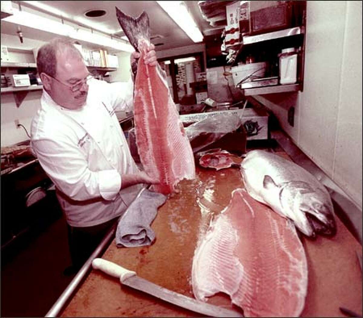 Ray's Boathouse executive chef Charles Ramseyer fillets a king salmon following a news conference yesterday. Opponents of genetically modified fish fear that they will put wild fish stocks at risk.