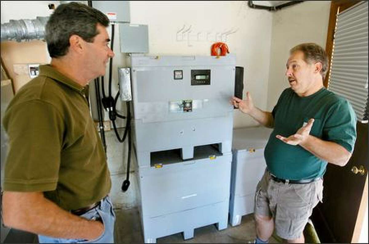 Bill Von Brethorst, right, explains the new solar system his crew had just installed for homeowner John Curtis, left.