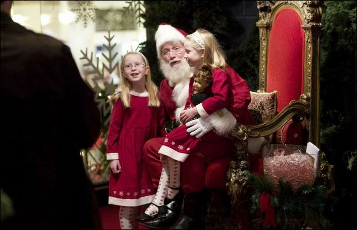 Lia, 8, left, and her sister, Zoe, 7, visit Santa as their parents, David Freeman and Nicole Ashford, watch Thursday at Macy's in downtown Seattle.