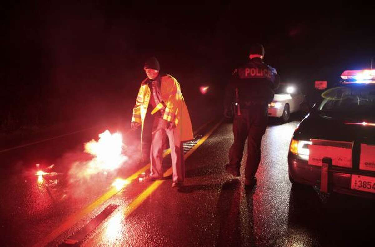 Washington State Patrol and Lakewood police officers light flares at a roadblock near the scene of a shooting that involved two Pierce County Sheriff's deputies, Monday, Dec. 21, 2009, near Eatonville. (AP Photo/Ted S. Warren)