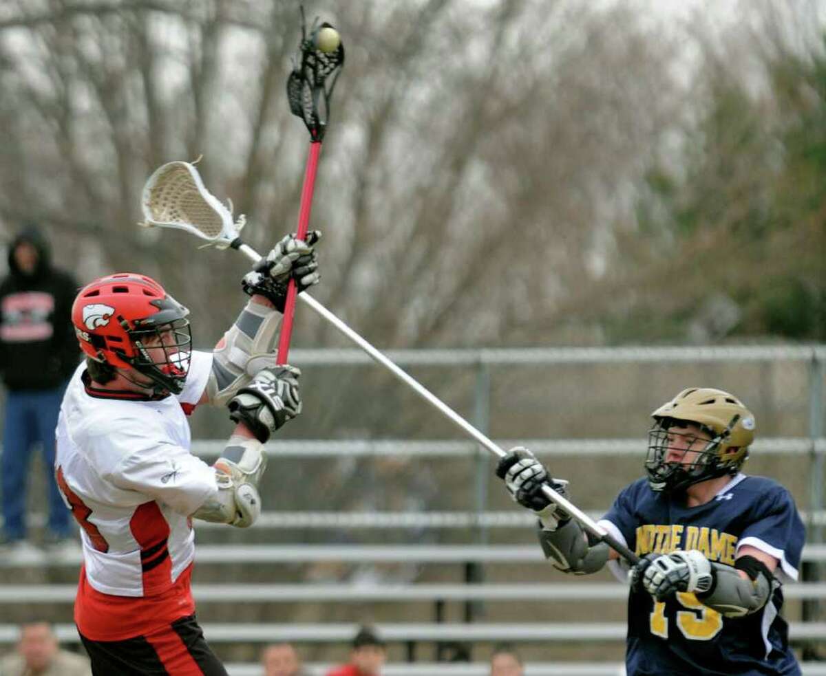 Masuk's #33 Connor Holloran, left, sends the ball in for one of the team's seventeen goals, as Notre Dame of Fairfield's #19 Jordan Garrison tries to block, during boys lacrosse action in Fairfield, Conn. on Wednesday April 6, 2011.