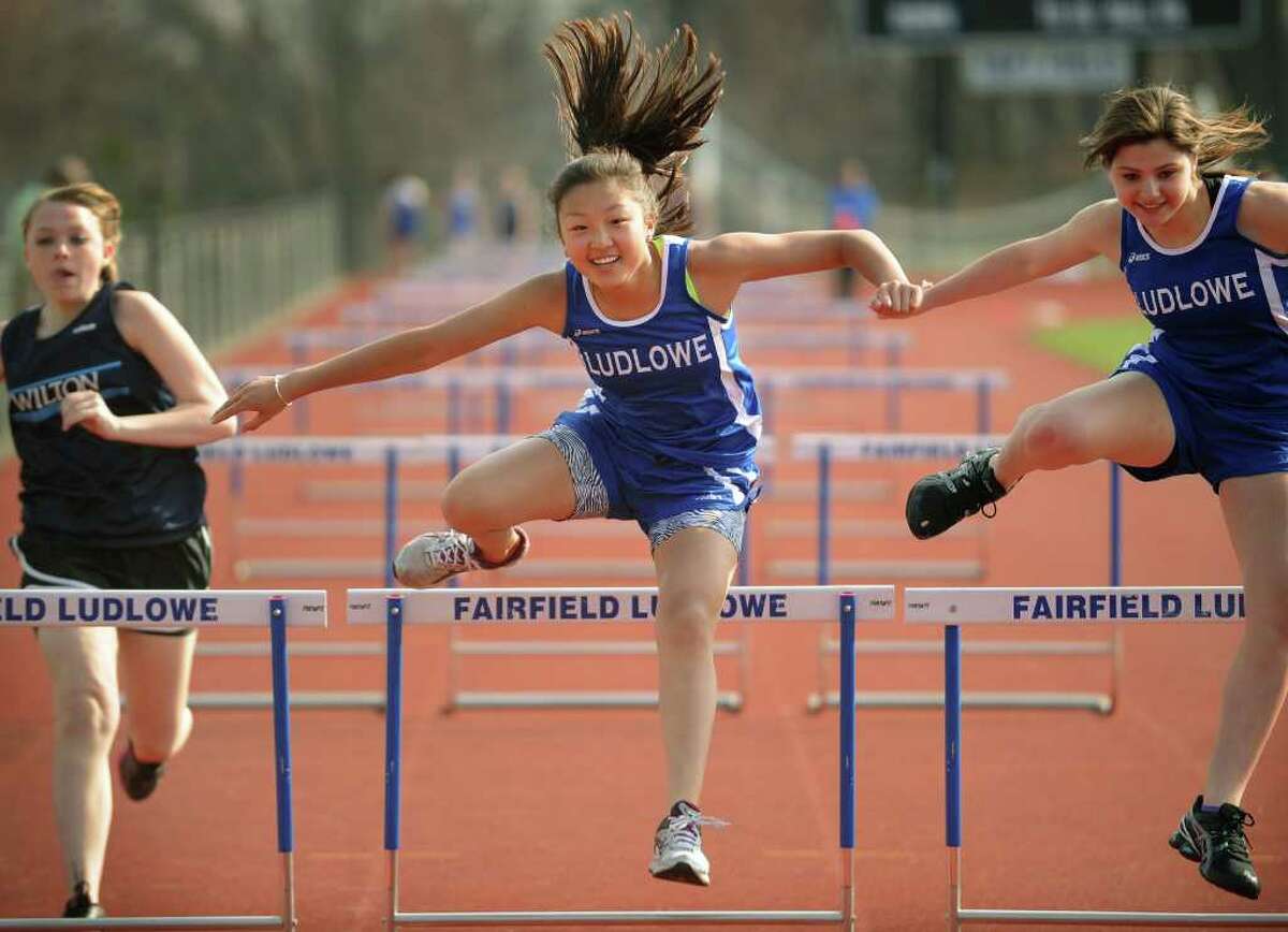 Fairfield Ludlowe's Miki Sakaguchi, center, wins her heat in the 100 meter hurdles during a meet with Wilton and Bassick at Ludlowe High School in Fairfield on Monday, April 11, 2011.