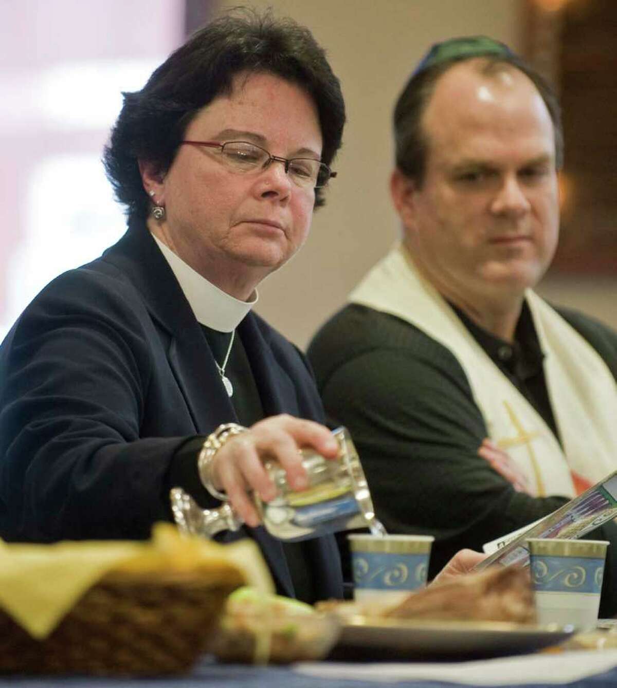 Rev. Kathleen Adams-Shephard of Trinity Episcopal Church pours water as part of the Passover Seder while Rev. Matt Crebbin of the Newtown Congregational Church observes during an interfaith celebration at Congregation Adath Israel in Newtown Sunday, April 10, 2011