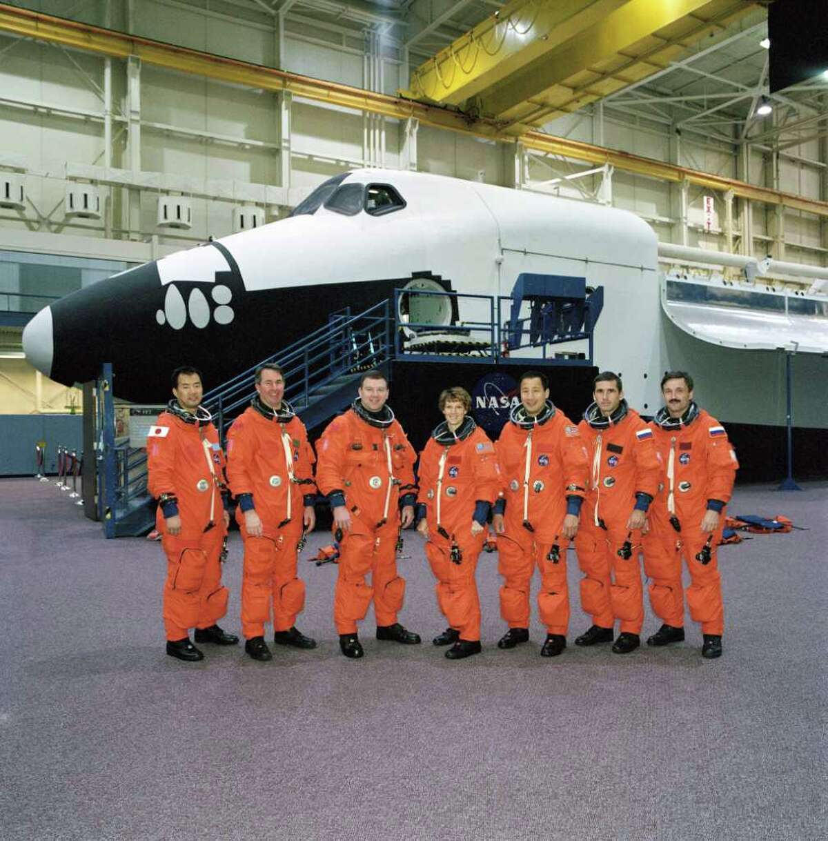 NASA's STS-114 and Expedition Seven crews, attired in training versions of the full-pressure launch and entry suit, pose for a group photo in front of the full-fuselage trainer prior to a training session on Nov. 12, 2002 in the Space Vehicle Mockup Facility at the Johnson Space Center, in Houston. From the left are astronauts Soichi Noguchi, Stephen K. Robinson, both STS-114 mission specialists; James M. Kelly, STS-114 pilot; Eileen M. Collins, STS-114 mission commander; Edward T. Lu, Expedition Seven flight engineer; cosmonauts Yuri I. Malenchenko, Expedition Seven mission commander; and Alexander Y. Kaleri, Expedition Seven flight engineer. Noguchi represents Japan's National Space Development Agency. Malenchenko and Kaleri represent Rosaviakosmos.
