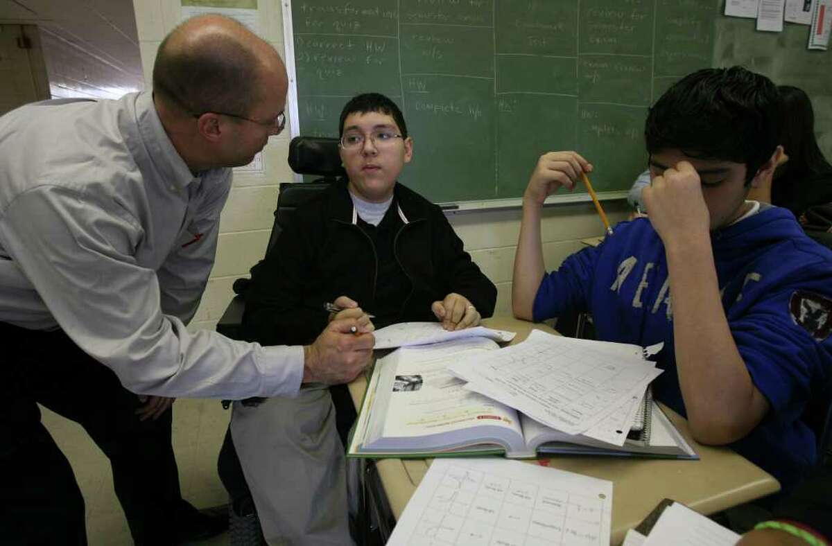 Burbank High School sophomore Jonathon Stach (center) works on his algebra with teacher Thad Flournoy (left) along with student Christopher Aragon,15 (right). Stach, who has spinal muscular atrophy, is in the school's International Baccalaureate program and is earning his credit for P.E. by being a scorekeeper for the school's freshman basketball team. JOHN DAVENPORT/jdavenport@express-news.net