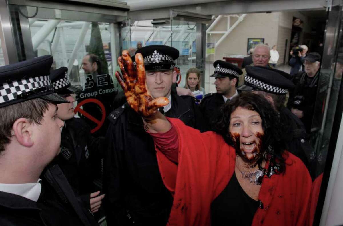 American Diane Wilson, from Texas, covered in oil, protests against BP as British police officers block her from entering the conference center where BP held its annual general meeting of its shareholders, in London, Thursday, April 14, 2011. BP's annual shareholder meeting got off to a rowdy start on Thursday as crowds of protesters watched over by police held noisy demonstrations outside the venue.