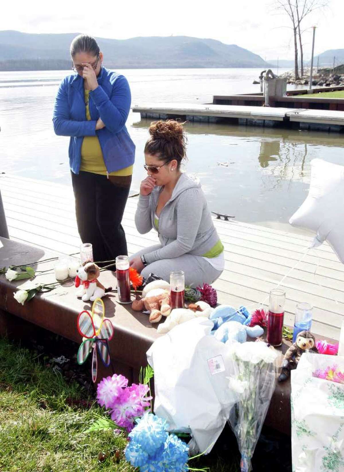Natasha Colon, left, and Nicole Callahan, both of Newburgh, N.Y., visit a memorial at the boat ramp where Lashanda Armstrong drove her minivan into the Hudson River on Tuesday night killing herself and three of her children, in Newburgh, on Thursday, April 14, 2011.