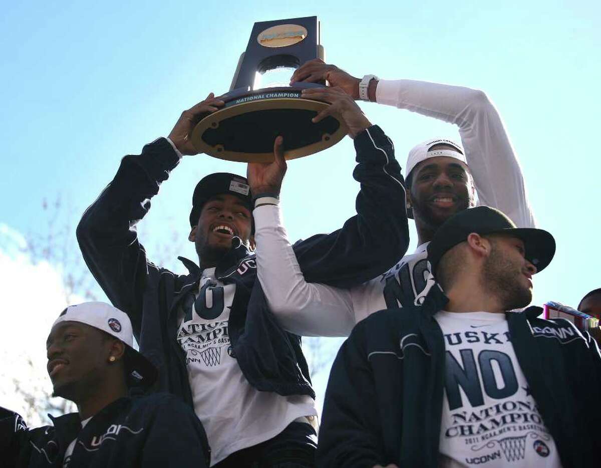 UConn players Jamal Coombs-McDaniel, second from left, and Alex Oriakhi, hoist the NCAA Championship trophy during the victory parade in Hartford on Sunday, April 17, 2011. At left is UConn star player Kemba Walker.