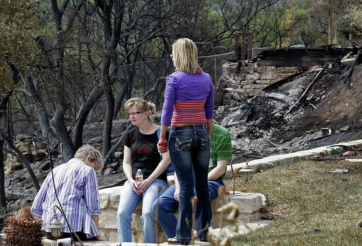 STATE – Kris Griffin, in black shirt and glasses, sits in her backyard with family members in the Oak Hills subdivision of West Austin, Monday, April 18, 2011. A 100-acres wildfire, is thought to have been started by a campfire at a homeless encampment Sunday morning, destroyed several homes. Her home was damage by the fire and compromise the roof structure. She was not allowed access to the inside due to safety issues. Michael Bernard Weathers, 60, has been charged with arson and is in the Travis County Jail on a $50,000 bail, according to the Austin American Statesman. JERRY LARA/glara@express-news.net