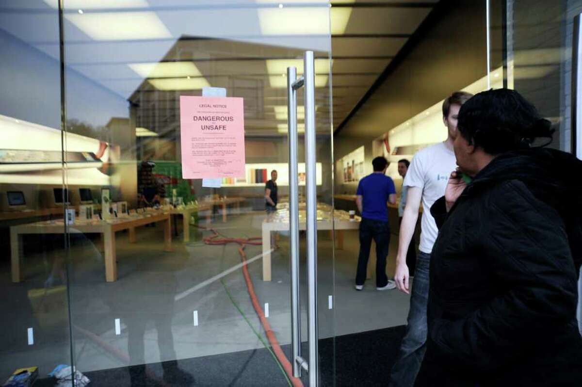 A woman looks a sign warning of unsafe conditions at on the Apple computer store on Greenwich Avenue on Wednesday, April 20, 2011. The store was flooded Tuesday night when a cleaning crew damaged a sprinkler.