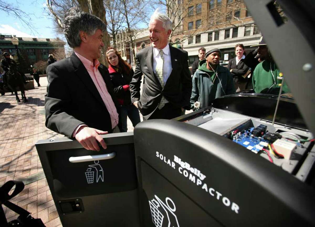 Rick Gaudett, left, director of sales for Big Belly Solar, shows Bridgeport Mayor Bill Finch a Big Belly Solar Compactor trash bin installed on McLevy Green in downtown Bridgeport on Thursday, April 21, 2011.