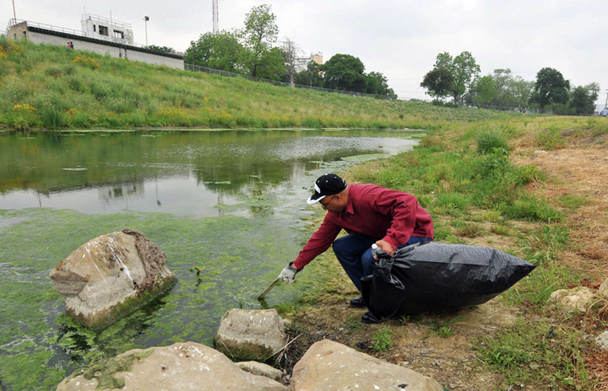 Brian Rawls cleans up trash along the San Antonio River near Roosevelt Park as part of the Armed Forces Earth Day campaign on Tuesday, April 19, 2011. The site south of downtown was chosen for the cleanup because litter from Fiesta revelry tends to collect there.
