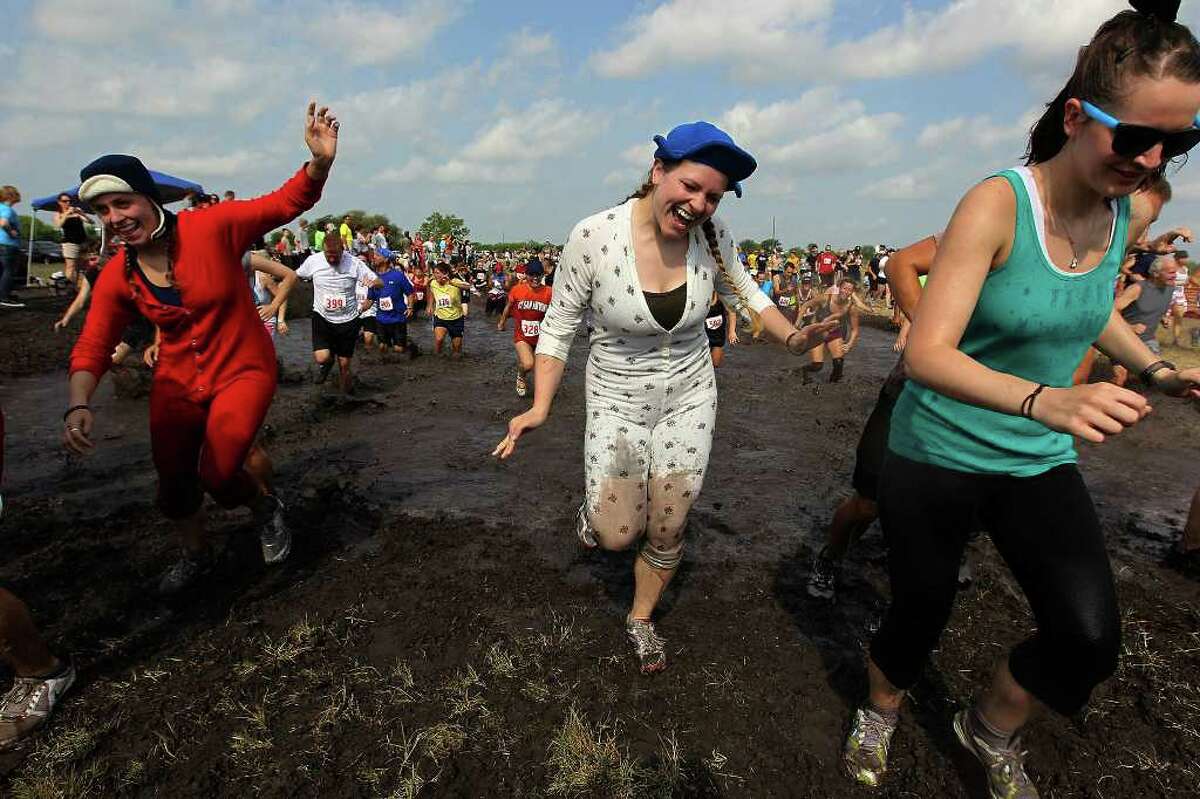 Elise Heck (center) and Caitlin Scarborough (left) join other runners in the Muddy Mayhem 8K run sponsored by The Athlete's Foot on Saturday, April 23, 2011. Runners dealt with several obstacles including a giant, muddy water hole near the finish. Over 1,000 runners participated in the fun yet mucky mess. Proceeds went to Wounded Warrior Project.