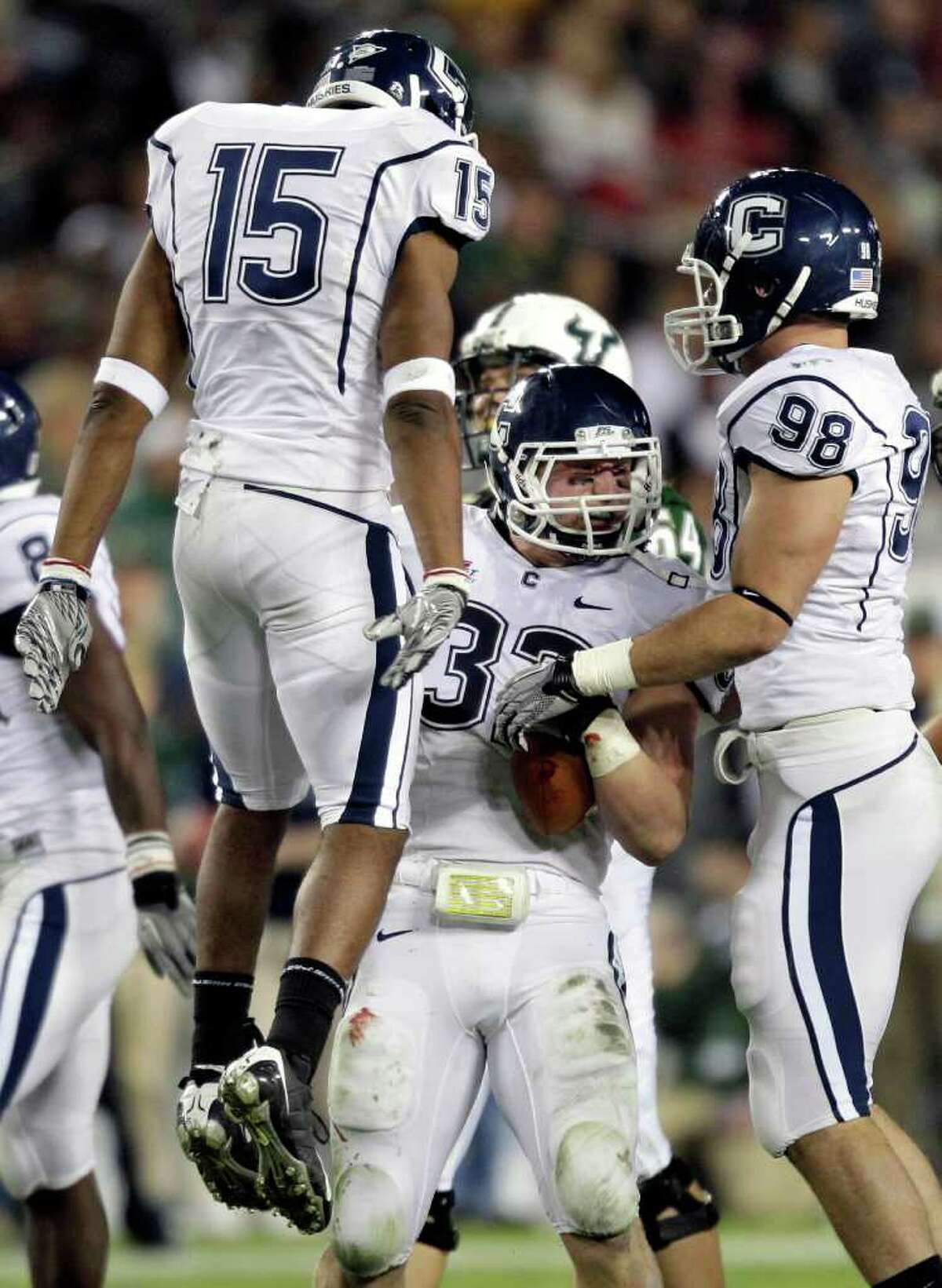 Connecticut linebacker Scott Lutrus (32) celebrates with teammates Jerome Junior (15) and Ted Jennings (98) after intercepting a South Florida pass during the first quarter of an NCAA college football game Saturday, Dec. 4, 2010, in Tampa, Fla. (AP Photo/Chris O'Meara)