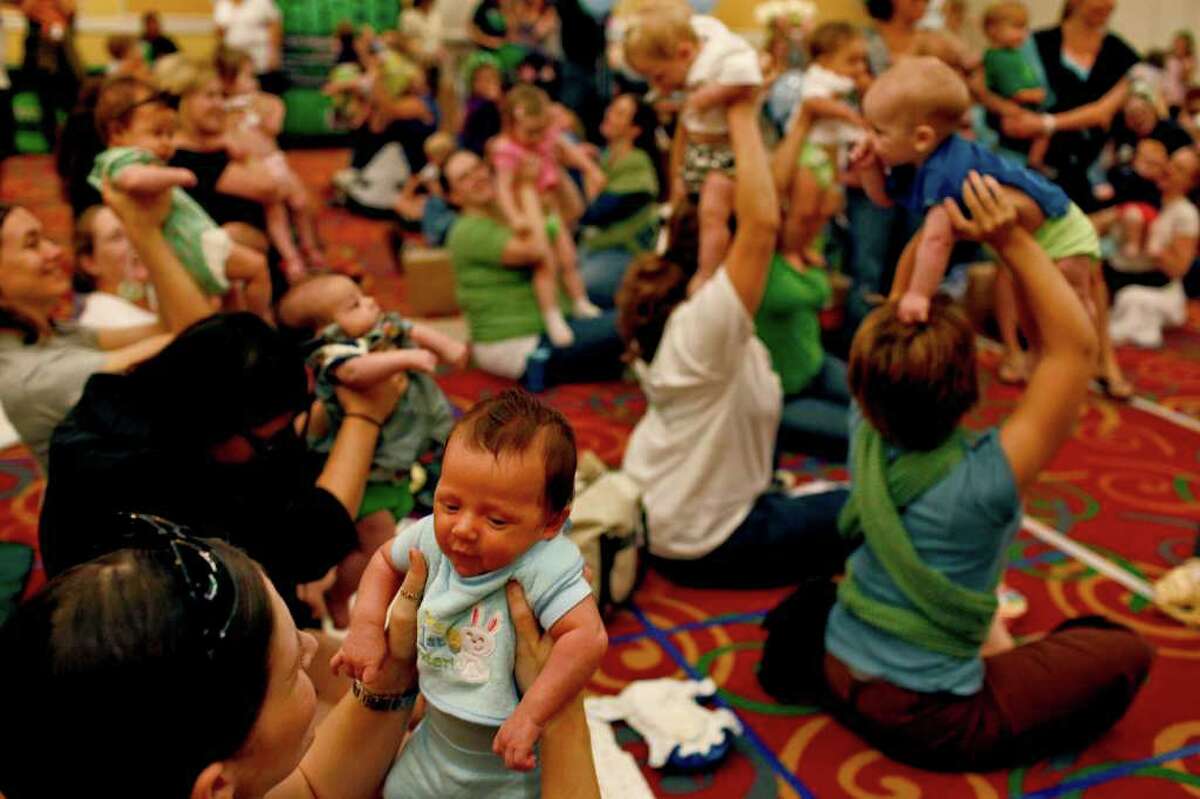 metro - Brooke Bueno holds up her son, Braxton Bueno, 6 weeks, as a photo is made to send to the Guinness World Records after Braxton and 72 other children had a diaper change during The Great Cloth Diaper Change at a La Quinta hotel in San Antonio on Saturday, April 23, 2011. LISA KRANTZ/lkrantz@express-news.net