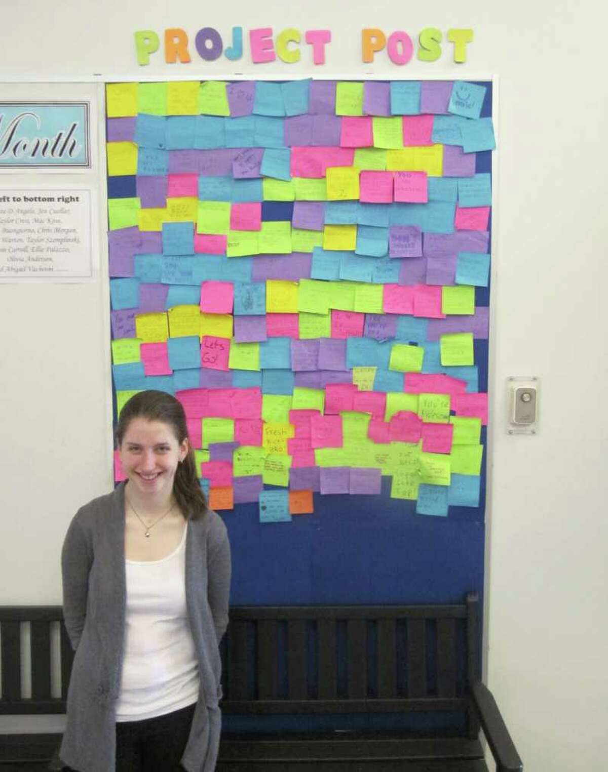 Melissa Warten,a junior at Fairfield University, stands in front of "Project POST," located in the high school's lobby. Back on April 11, students were encouraged to write nice things about people without signing their name or naming names. The hope is promote tolerance and acceptance in the high school setting.