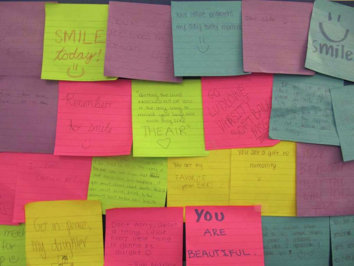 Pictured are a number of the "Project POST" Post-It notes on a bulletin board in the lobby of Fairfield Ludlowe High School.