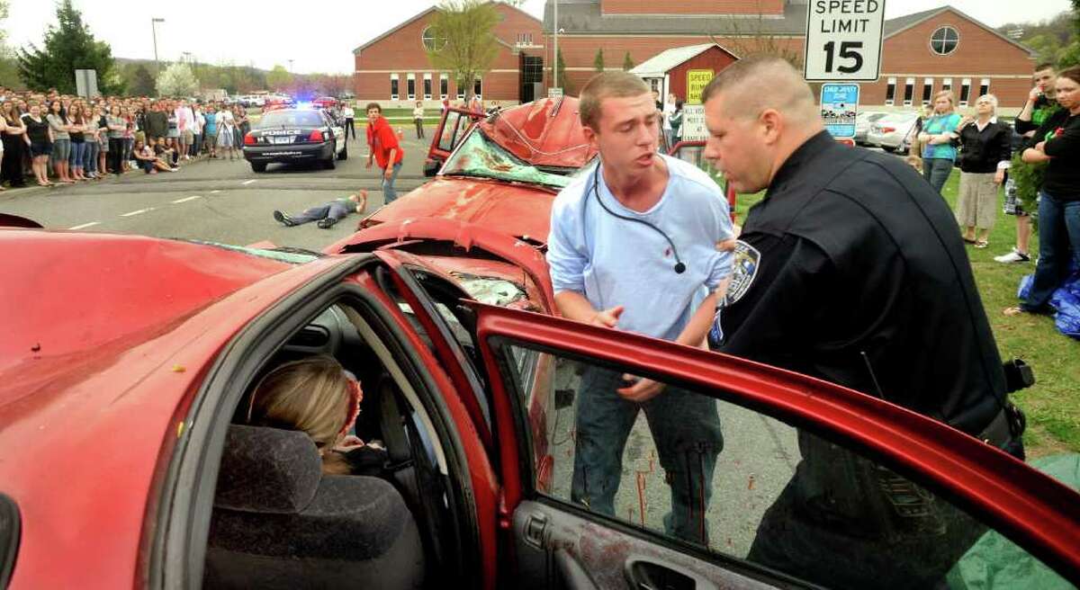 Nick Gruder, 18, is held back from his dead passenger by police officer Brian Bollaro during a mock crash staged at New Milford High School by Students Against Destructive Decisions, Thursday, April 28, 2011.