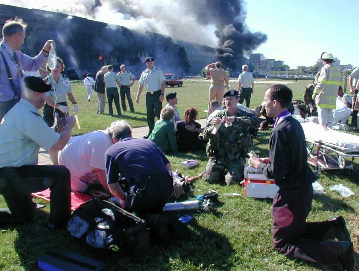 A priest prays over a wounded man outside the west entrance of the Pentagon as emergency workers from all services mobilize to help the wounded Tuesday, Sept. 11, 2001 after a terrorist attack in Arlington, Va.