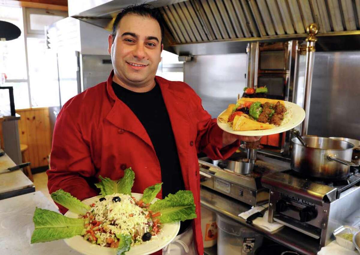 Chef and owner Yusuf Uzun holds his shepherd's salad and lamb shish kebab dishes at Bereket Turkish restaurant, located behind the Citgo gas station at 4031 Main St. in Bridgeport, Conn.