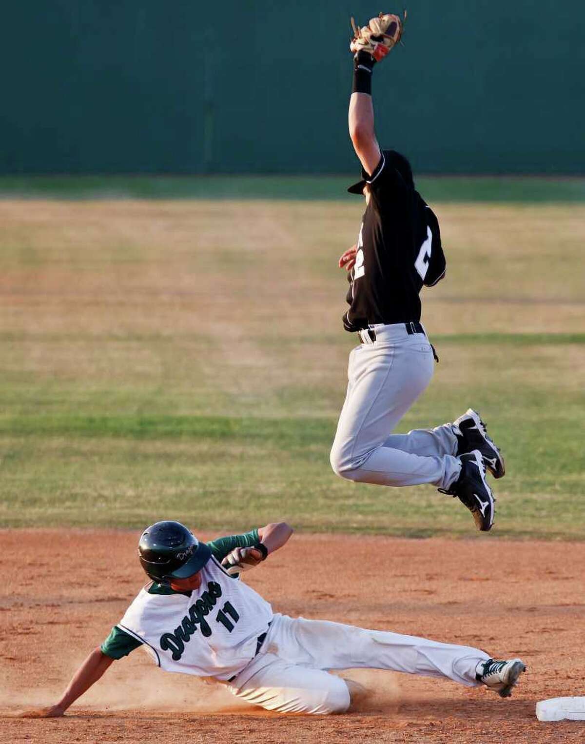 Clark shortstop Jason Cervantes leaps high into the air to catch a throw from third base as Southwest's Edgar Vaszuez slides safely back to second base during the Cougar's 3-2 first round playoff victory over the Dragons at Northside Field #2 on May 5, 2011. MARVIN PFEIFFER/mpfeiffer@express-news.net