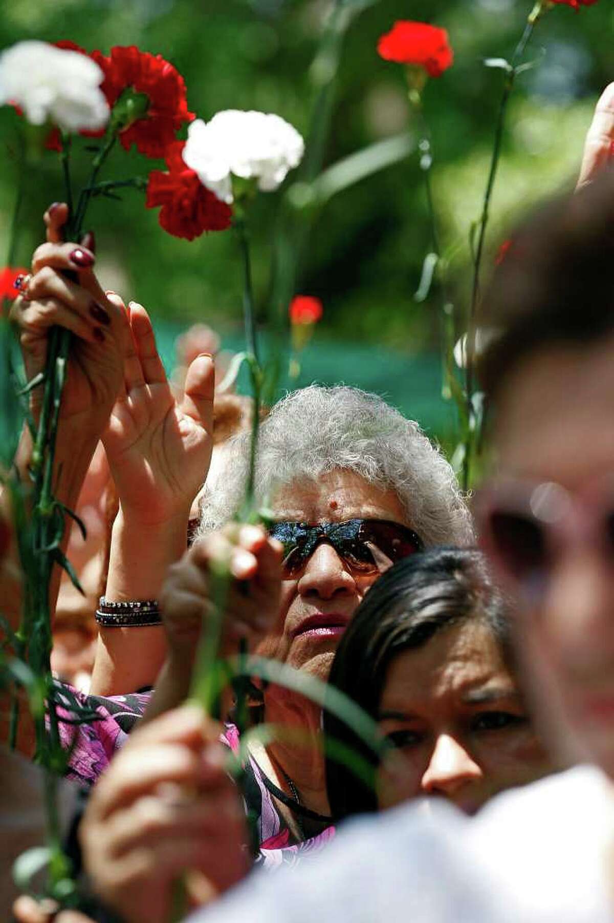 METRO – Alicia Anzaldua Salinas, 74, wearing glasses, holds up her carnation along with other mothers during a blessing after the Mother's Day Mass at Our Lady of Lourdes Grotto, Sunday, May 8, 2011. JERRY LARA/glara@express-news.net