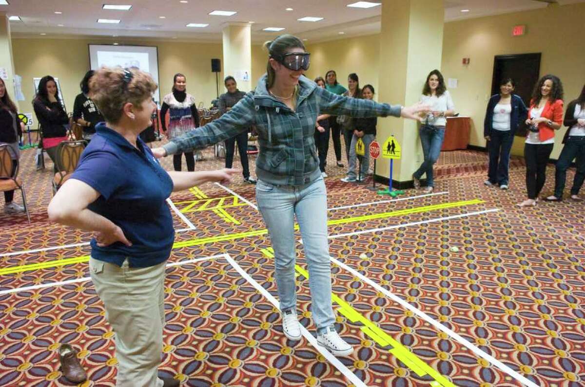 Fran Mayko guides au pair Carla Maria Rocco or Brazil as she walks the line wearing goggles to simulate alcohol intoxication as the Automobile Association of America and Au Pair in America team up for a program to help au pairs become better drivers at the Holiday Inn Select in Stamford, Conn., May 8, 2011. The program covered American laws regarding child seats, street signs, and alcohol intoxication.