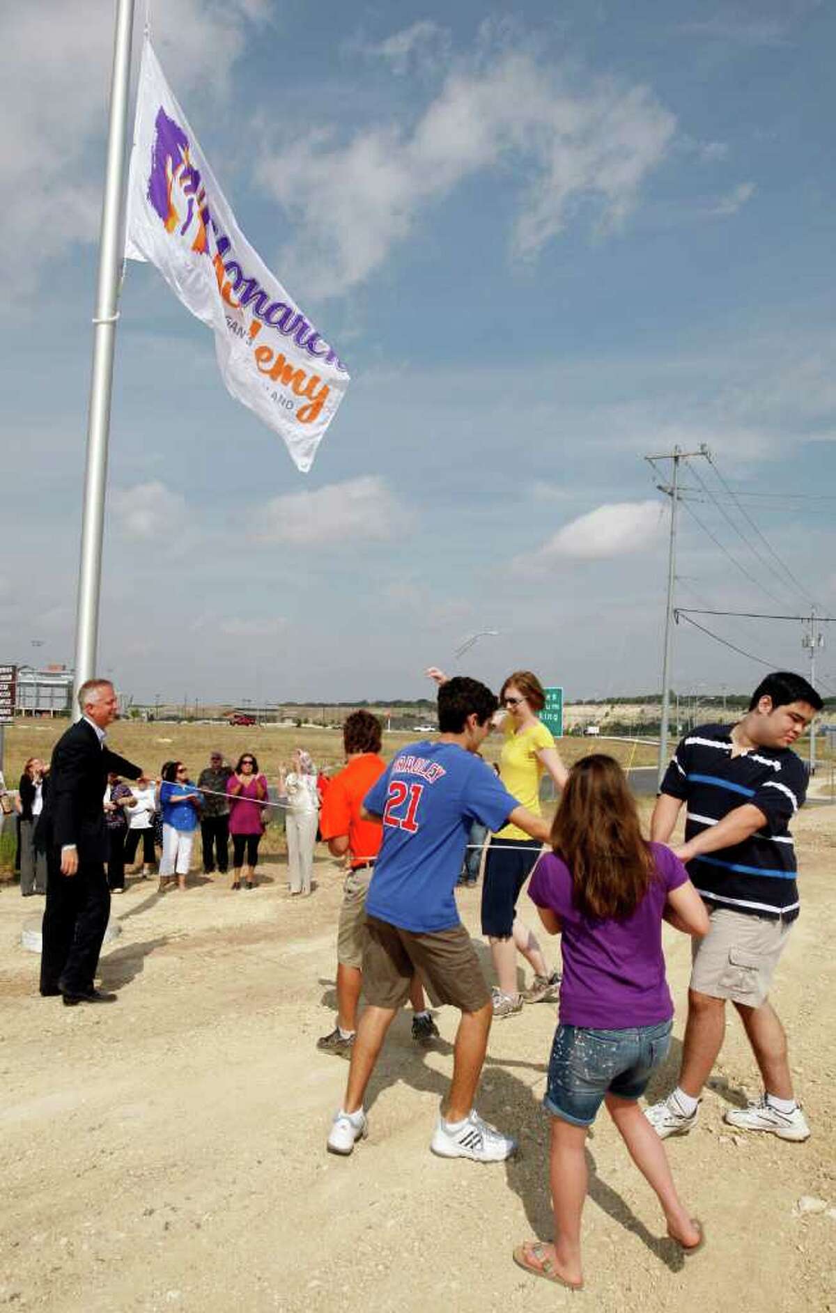Gordon Hartman (left) guides special needs students as they raise the flag for the Monarch Academy. The school, for special needs students, will sit on 2.3 acres next to the 25-acres Morgan's Wonderland. It is scheduled to open this August 22 and will start with a student body of 35. It is accepting applications for students between the sixth grade and 18 years of age as of Sept. 1, 2011. Although construction for the school is just starting, classes will begin in portable buildings. JERRY LARA/glara@express-news.net