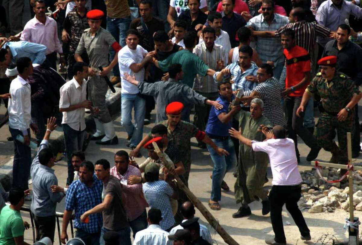 Egyptian Coptic Christians stop a man trying to throw a stone during clashes in front of the state television building where they protest recent attacks on Christians and churches in Cairo, Egypt, Sunday, May 15, 2011. Egypt's top Christian leader called on his followers Sunday to end a weeklong sit-in in front of a government building on the Nile after a mob attacked the Christian protesters and their supporters, injuring 67. (AP Photo/Khalil Hamra)