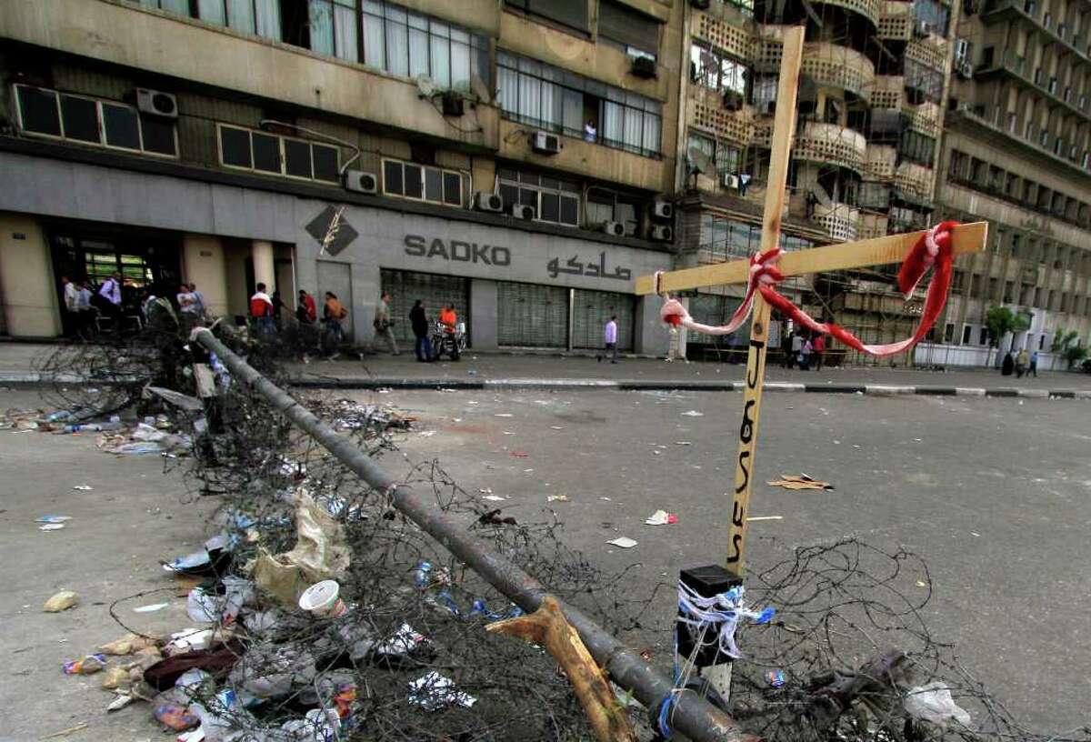 Egyptian Coptic Christians set a wooden cross on razor-wire and barricades they block the streets with, as they protest the recent attacks on Christians and churches, in front of the state television building in Cairo, Egypt, Sunday, May, 15, 2011. An angry mob attacked a group of mainly Christian protesters demanding drastic measures to heal religious tension amid a spike in violence, leaving 65 people injured, officials said Sunday. (AP Photo/Khalil Hamra)